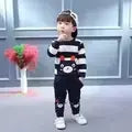 Toddler wearing a navy and white striped bear graphic sweatshirt and matching jogger pants with white sneakers