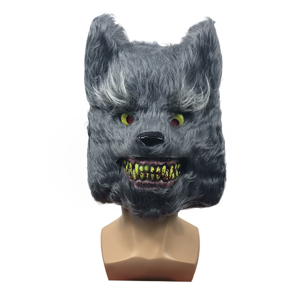 Gray wolf mask with green eyes and yellow teeth on a mannequin head against a white background