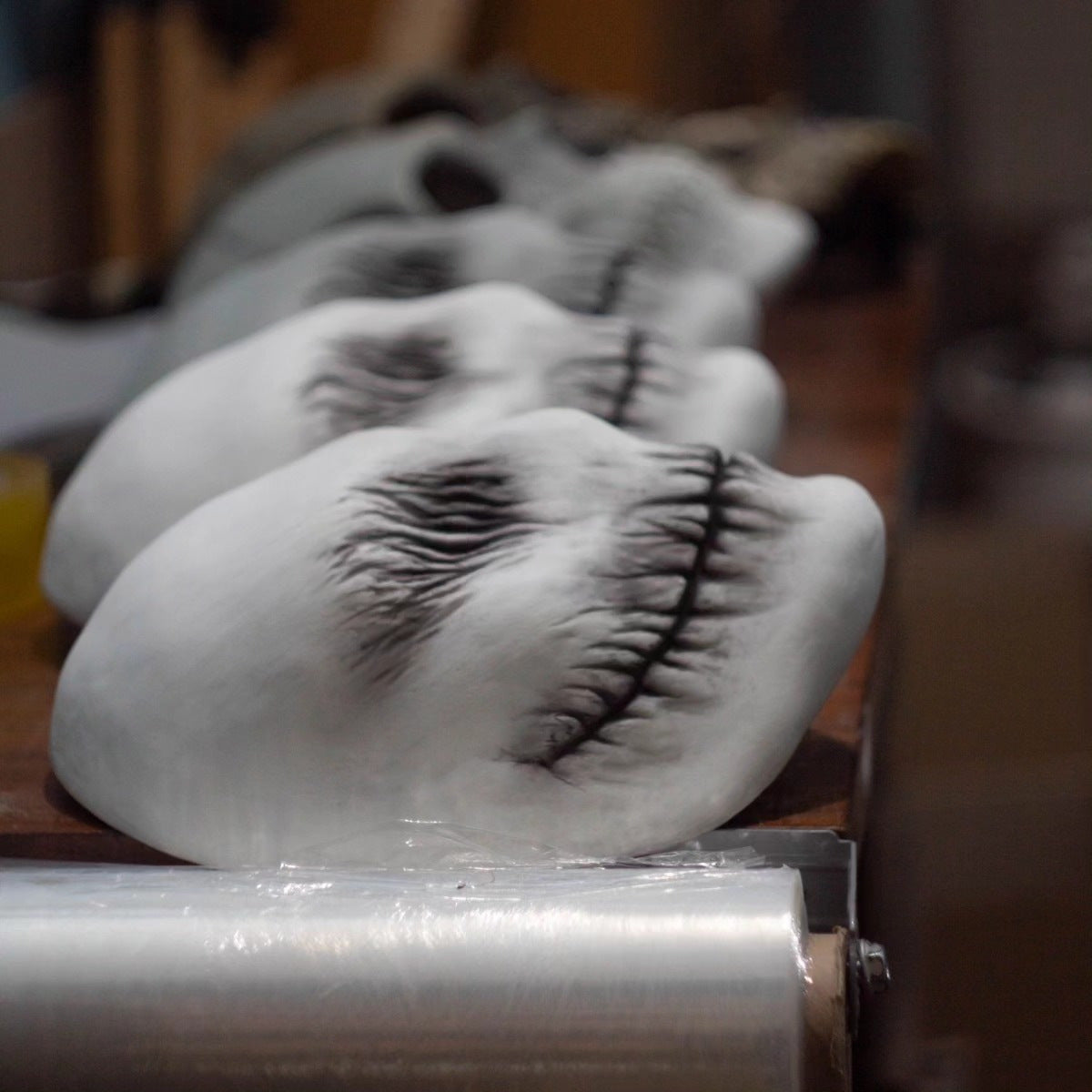 Eyelashes on a wooden board with a roll of plastic wrap in the foreground.