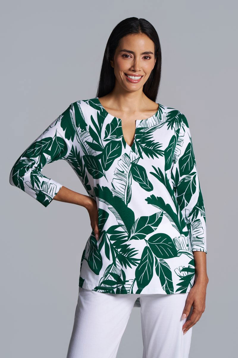 Woman wearing a green and white leaf-patterned blouse against a gray background