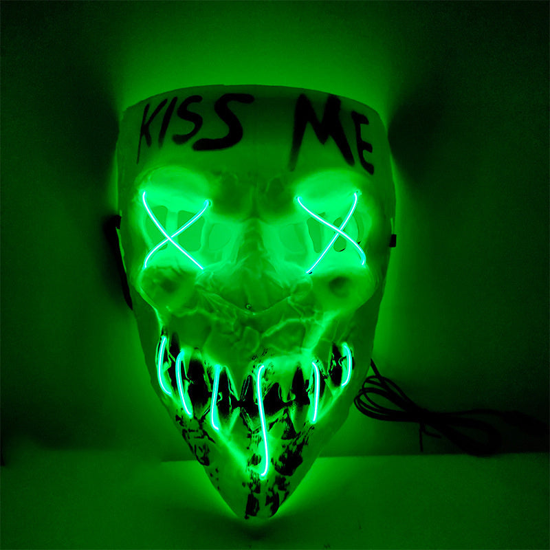 Glowing green skull mask with 'KISS ME' text on a dark background