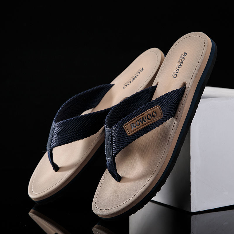Pair of sandals with navy straps on a reflective surface with a black background