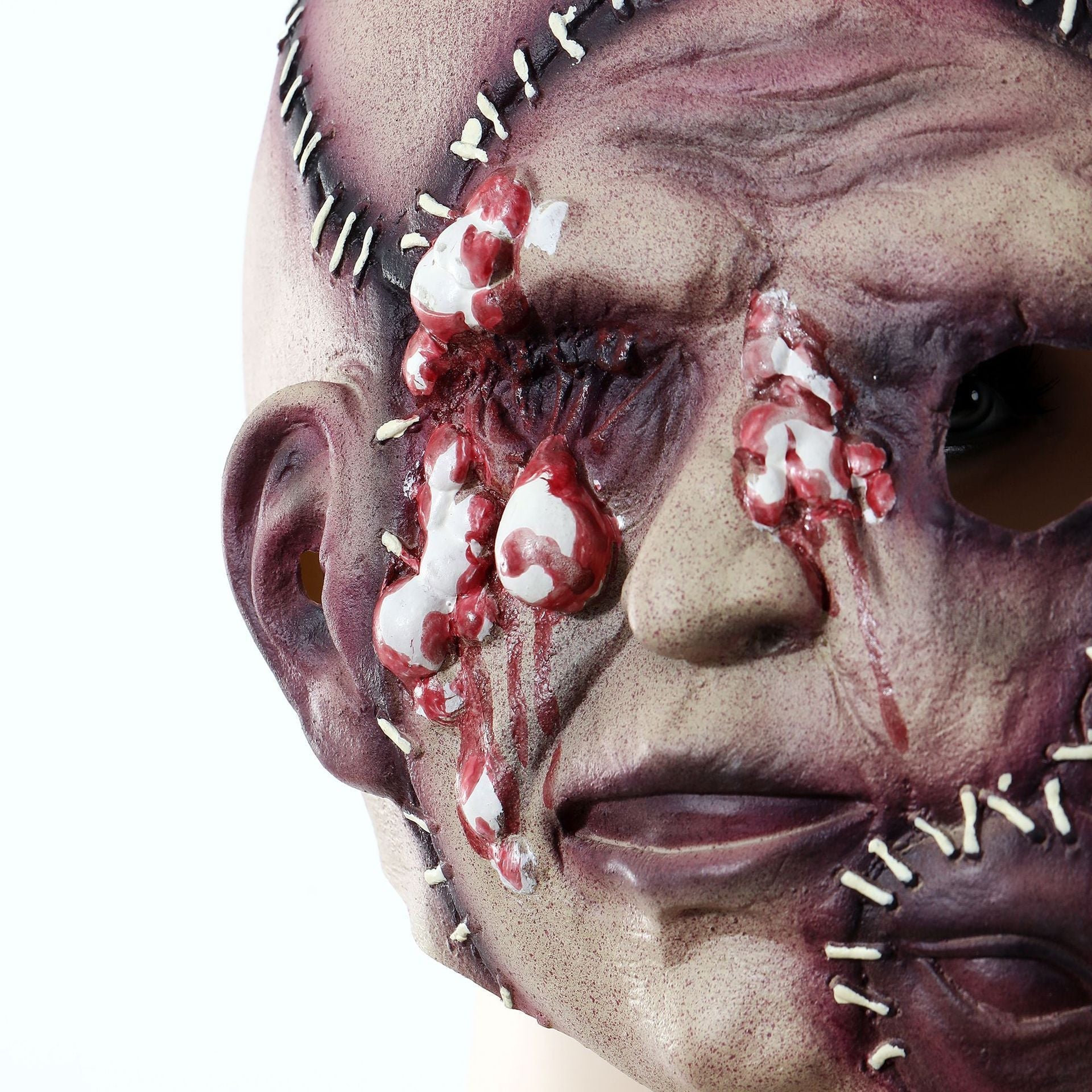 Close-up of a horror-themed mask with wounds and stitches on a white background