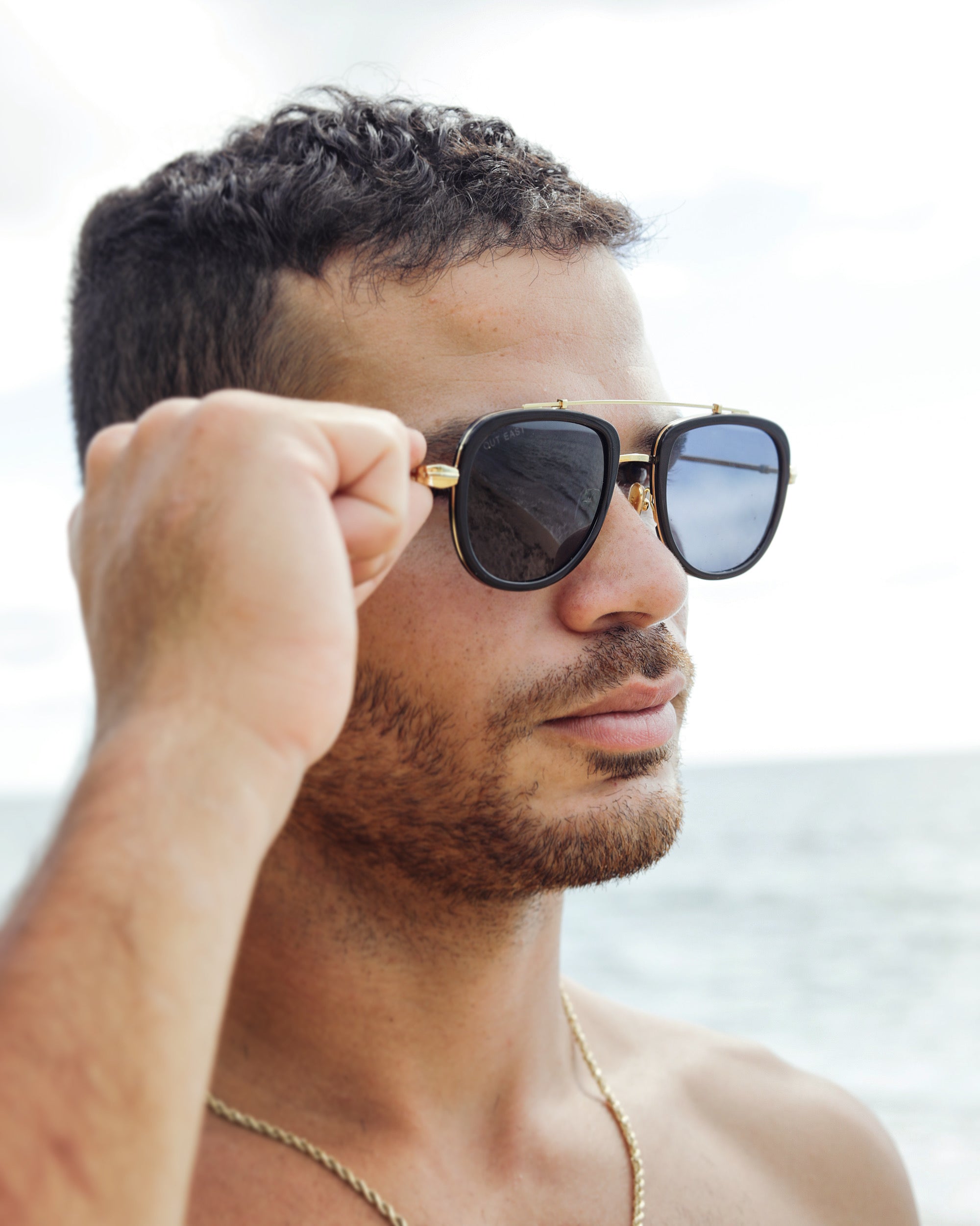 Man adjusting sunglasses with a blurred background