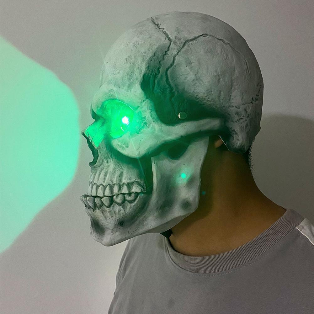 Skull mask with glowing green eyes on a plain background