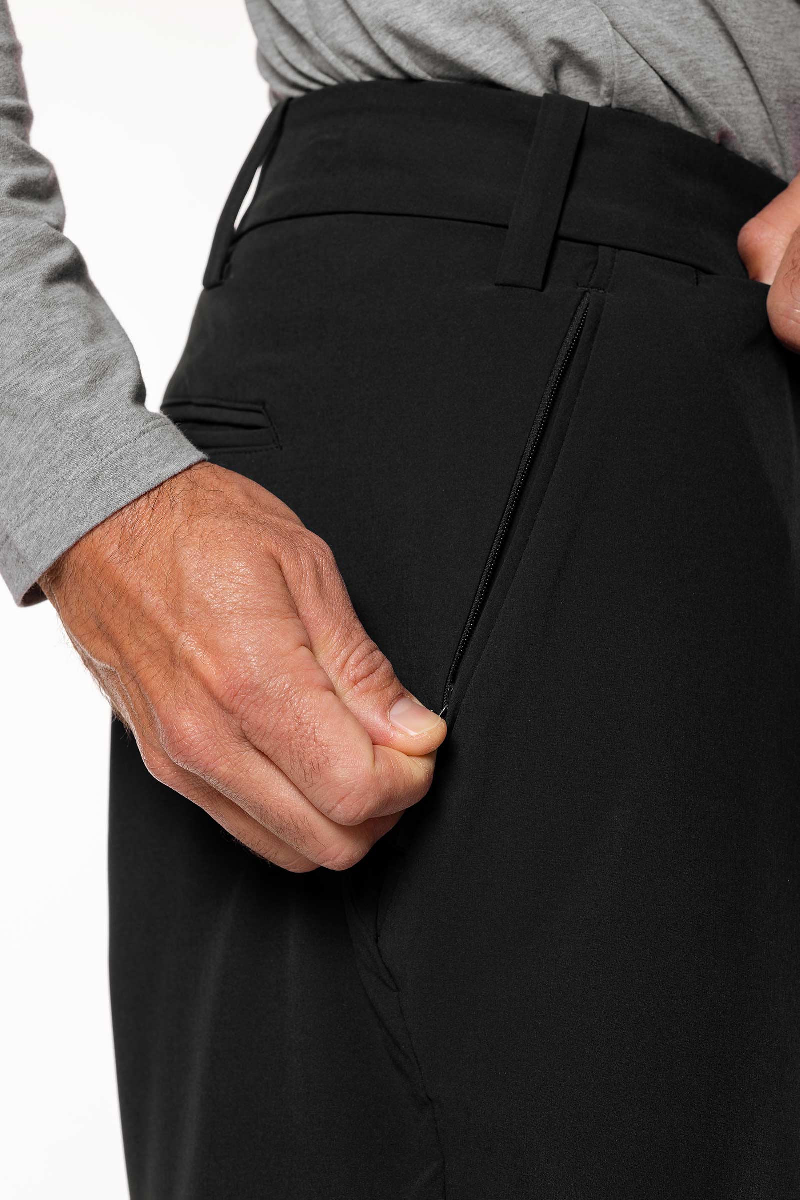 Close-up of a person wearing black pants with a gray shirt sleeve.