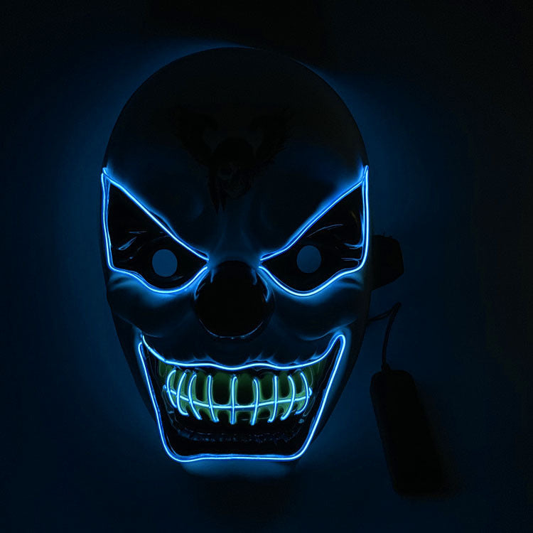 Neon blue and green mask with glowing teeth on a dark background