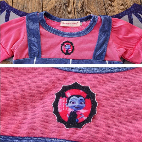Pink shirt with denim overalls and embroidered character on a wooden surface