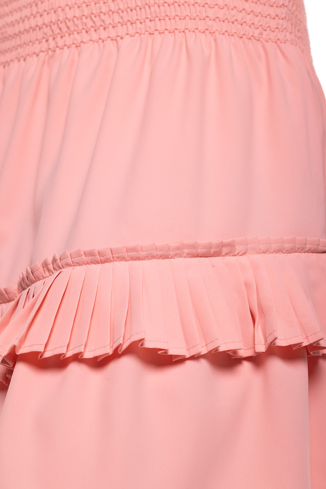 Close-up of a pink dress with smocked waistband and ruffled hem.
