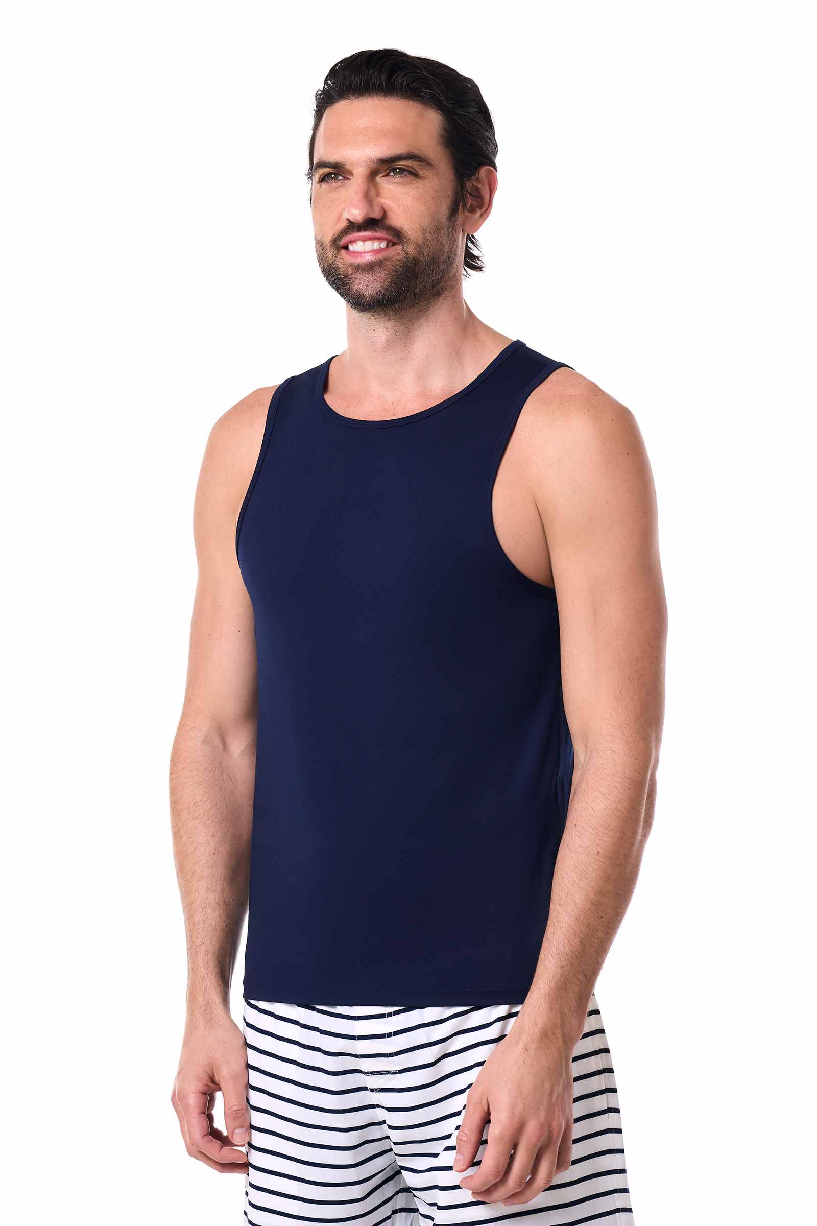 Man wearing a navy blue sleeveless shirt and striped shorts on a white background