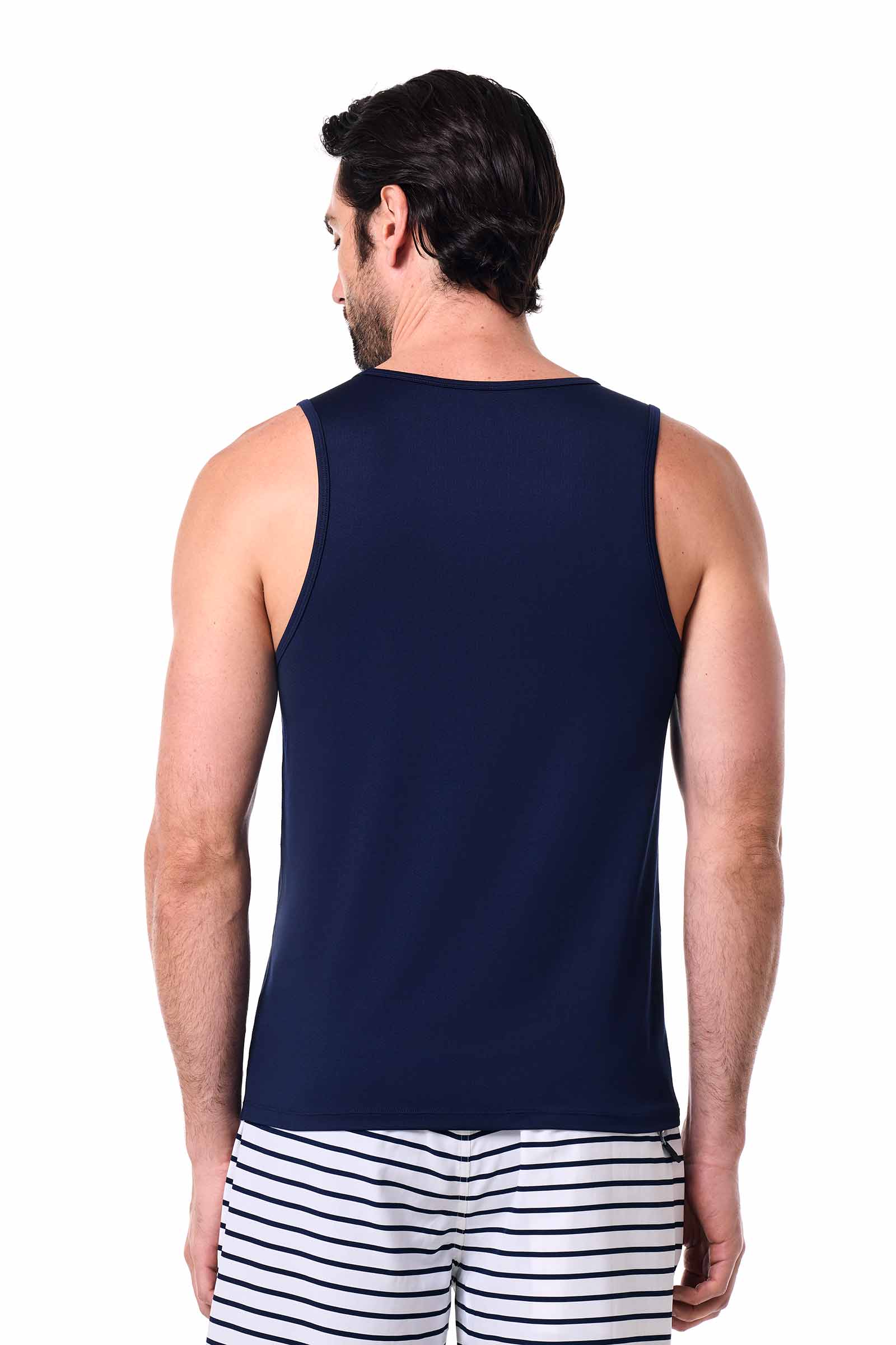 Man wearing a navy sleeveless shirt and striped shorts on a white background