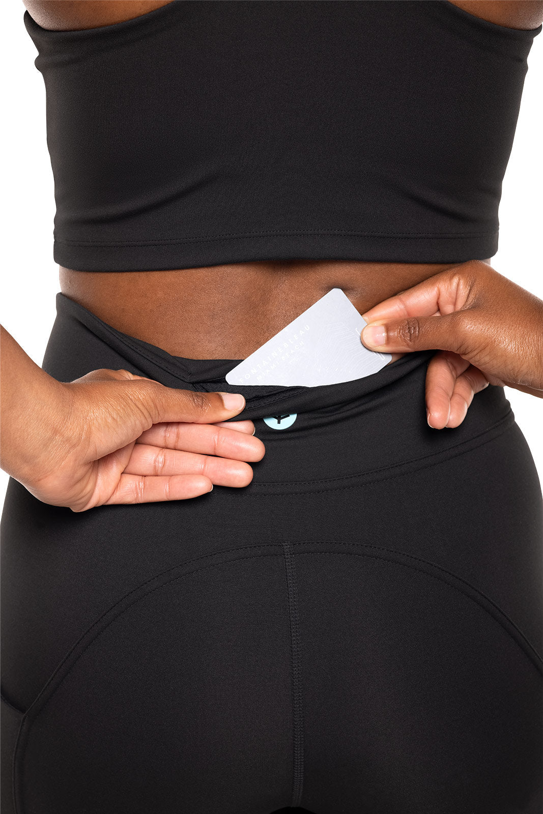 Person wearing black athletic pants with a white card in the waistband.