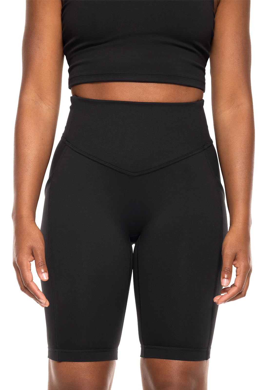 Person wearing black athletic shorts and crop top on a white background