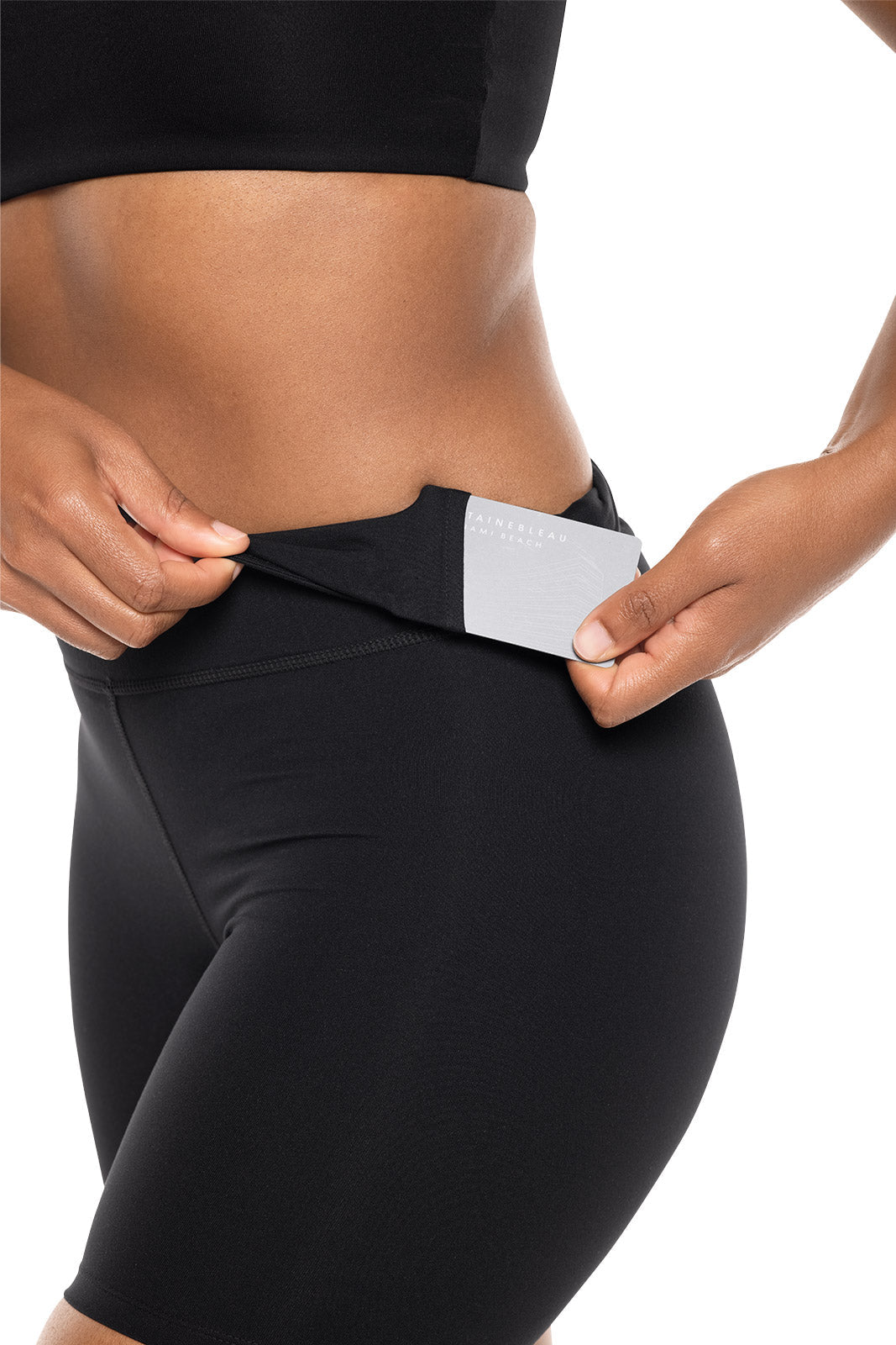 Person wearing black leggings with a white label on a light gray background