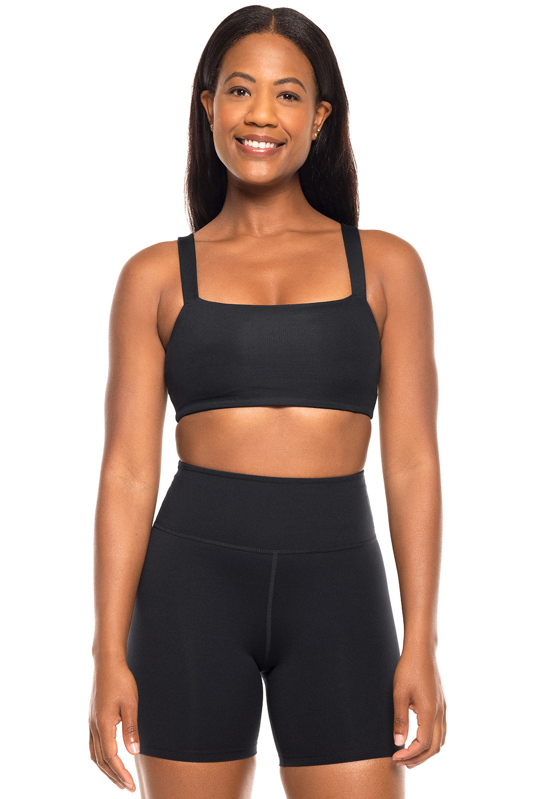 Woman wearing a black sports bra and shorts on a white background
