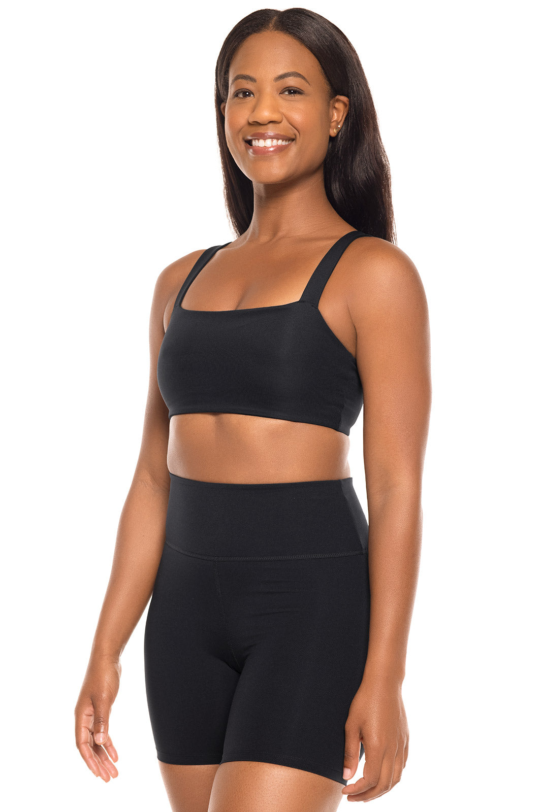 Woman wearing a black sports bra and shorts set on a white background