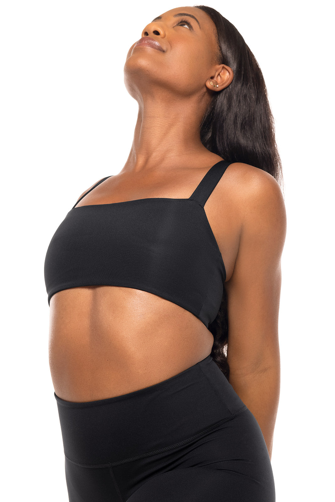 Woman wearing a black sports bra and leggings on a white background