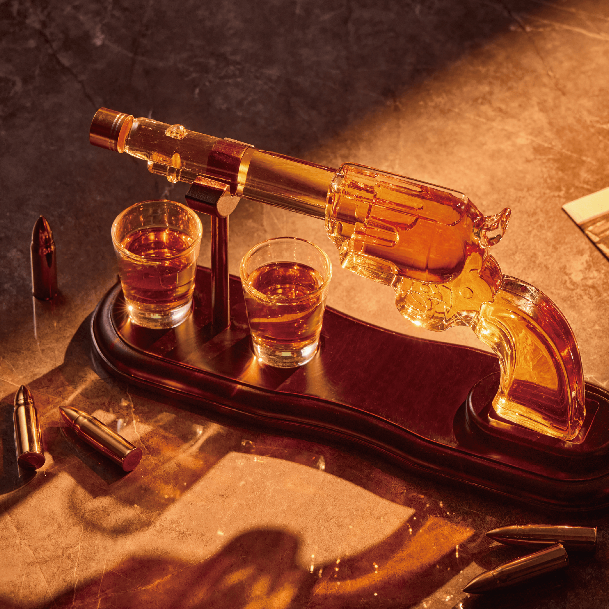 Glass revolver decanter with two shot glasses on a wooden tray, surrounded by bullet-shaped shot glasses.