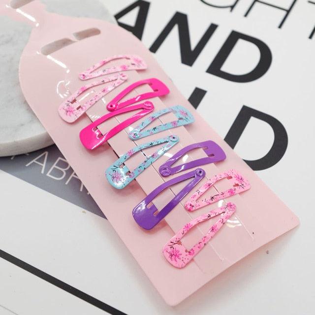 Set of colorful hair clips on a pink card with text in the background
