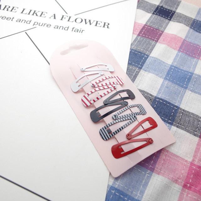 Set of colorful hair clips on a pink card with a plaid fabric background