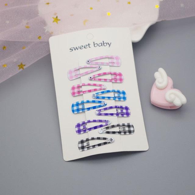 Set of colorful hair clips on a card with 'sweet baby' text, placed on a gray surface.