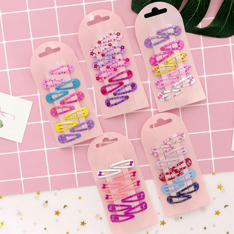 Set of colorful hair clips in pink packaging on a pink grid background