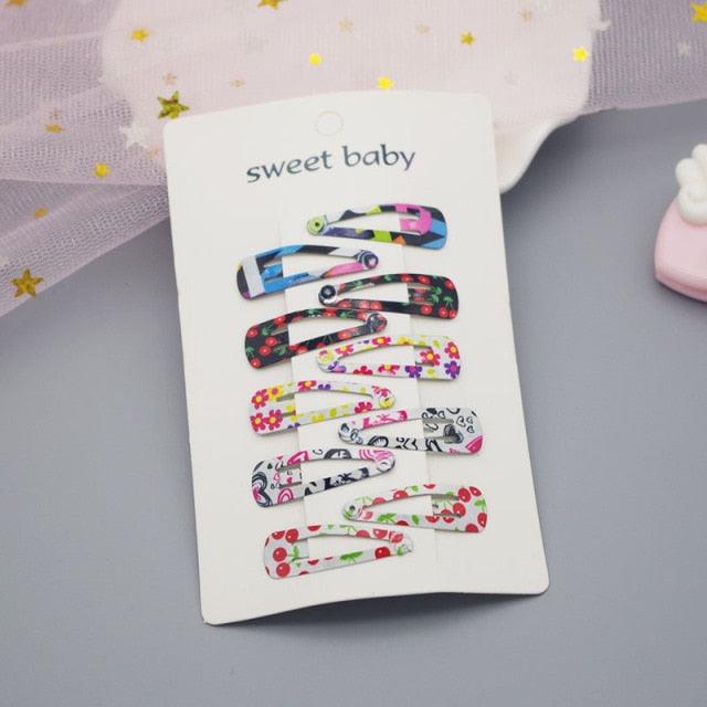 Set of colorful hair clips on a 'sweet baby' branded card against a light background.