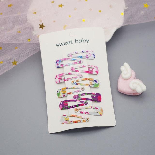 Colorful hair clips on a card with 'sweet baby' text, placed on a gray surface.
