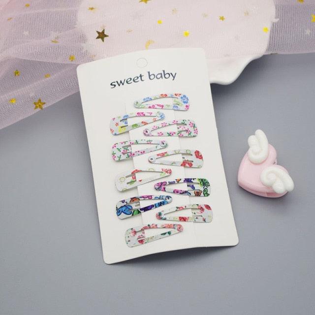 Set of colorful hair clips on a card with 'sweet baby' text, placed on a gray surface.