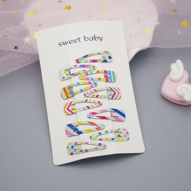 Colorful hair clips on a 'sweet baby' branded card with a soft background