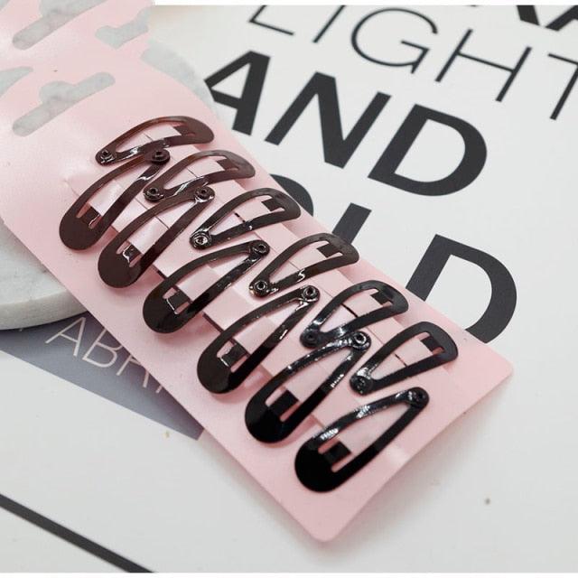 Set of black hair clips on a pink card with text in the background