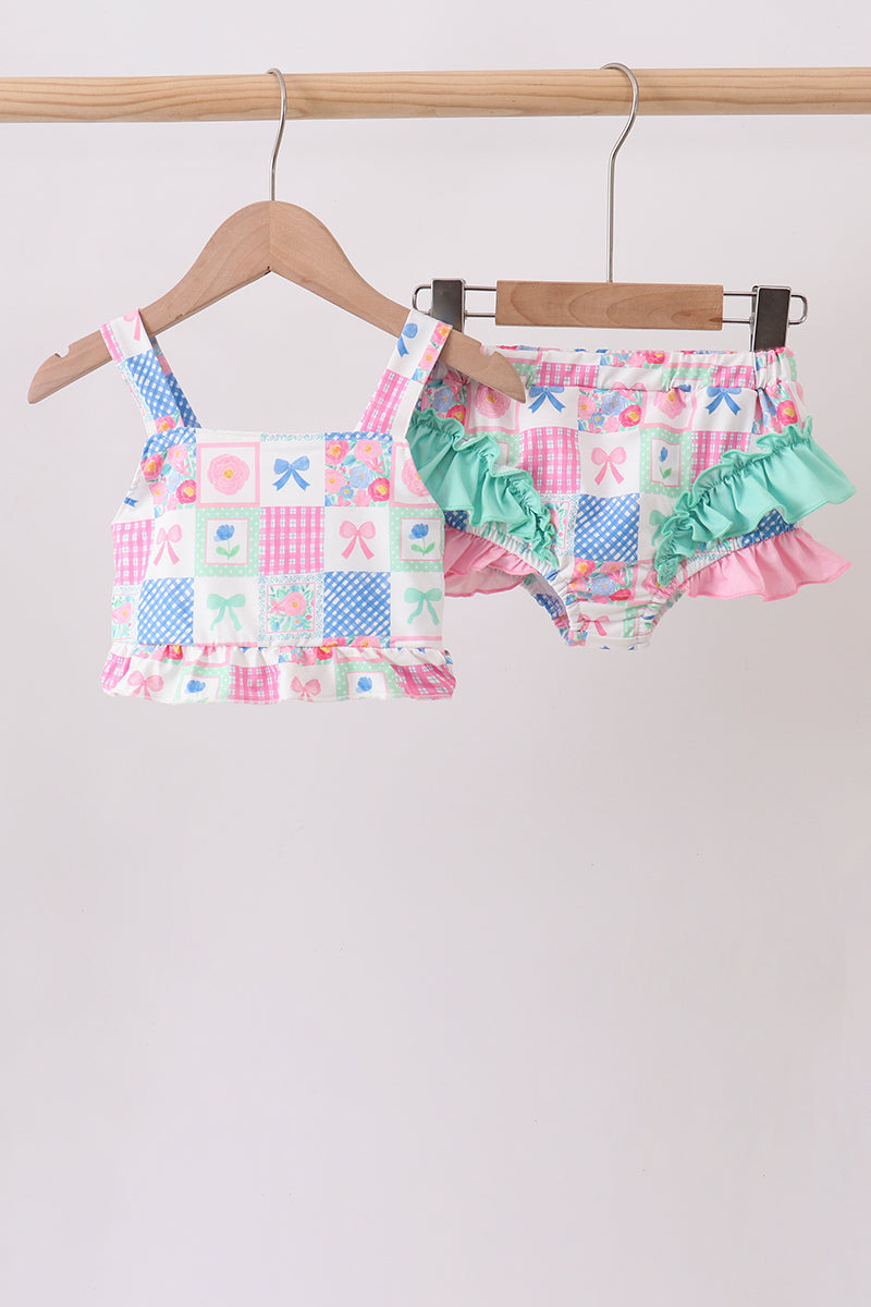 Children's patterned top and shorts set on hangers against a neutral background