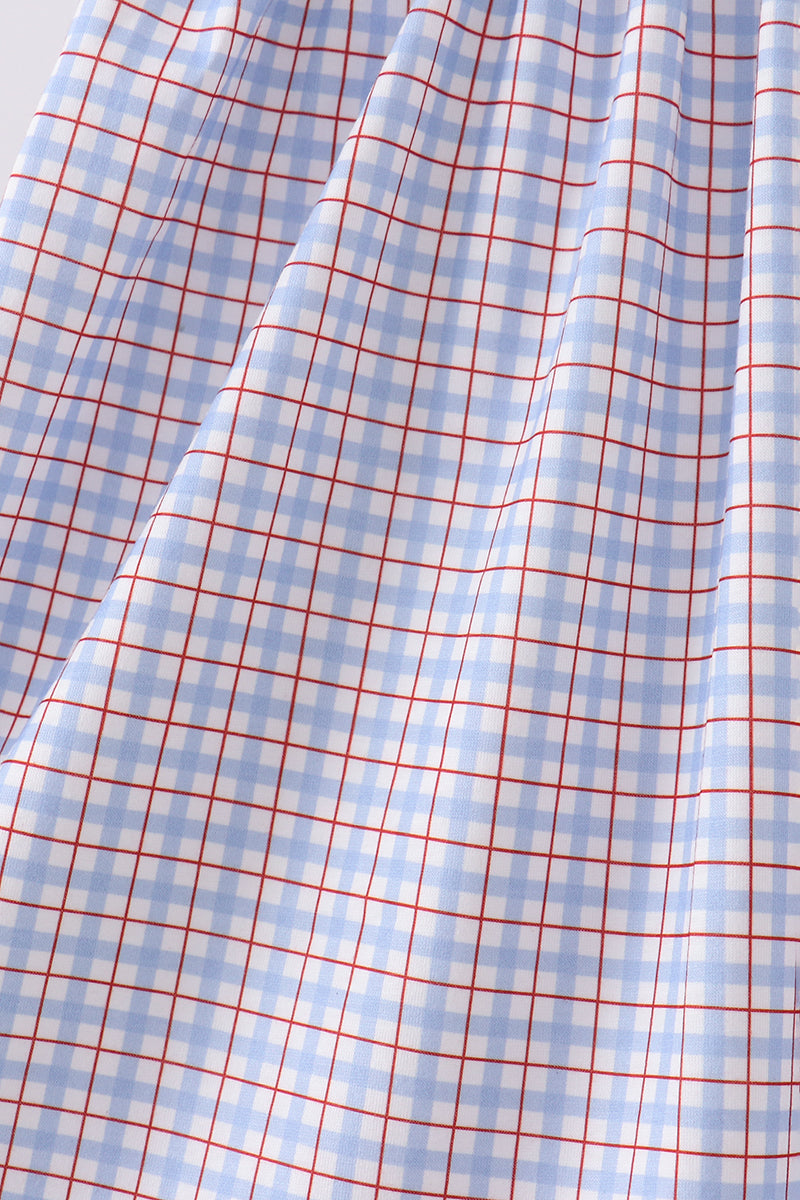 A close-up of draped fabric with a light blue and white gingham check pattern overlaid with thin red grid lines.