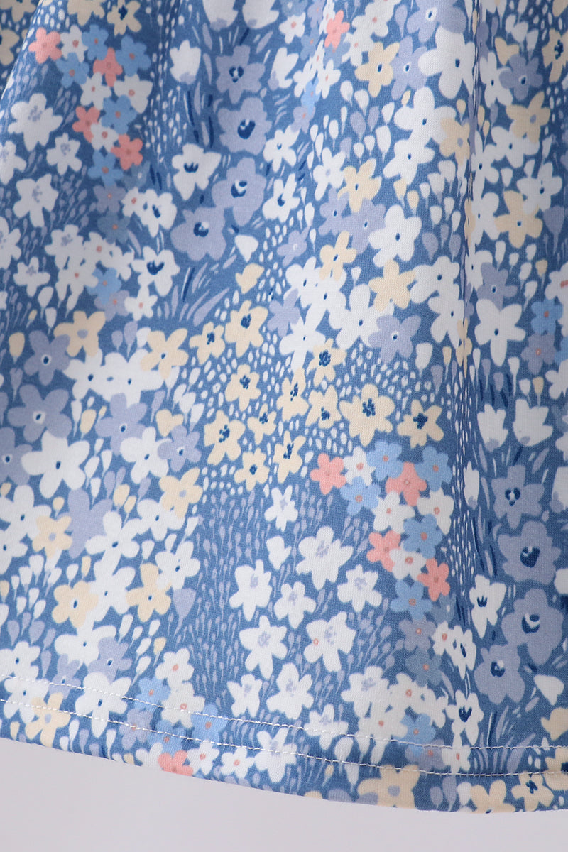 Close-up of a blue floral fabric with a dense pattern of small white, light blue, yellow, and pink flowers.