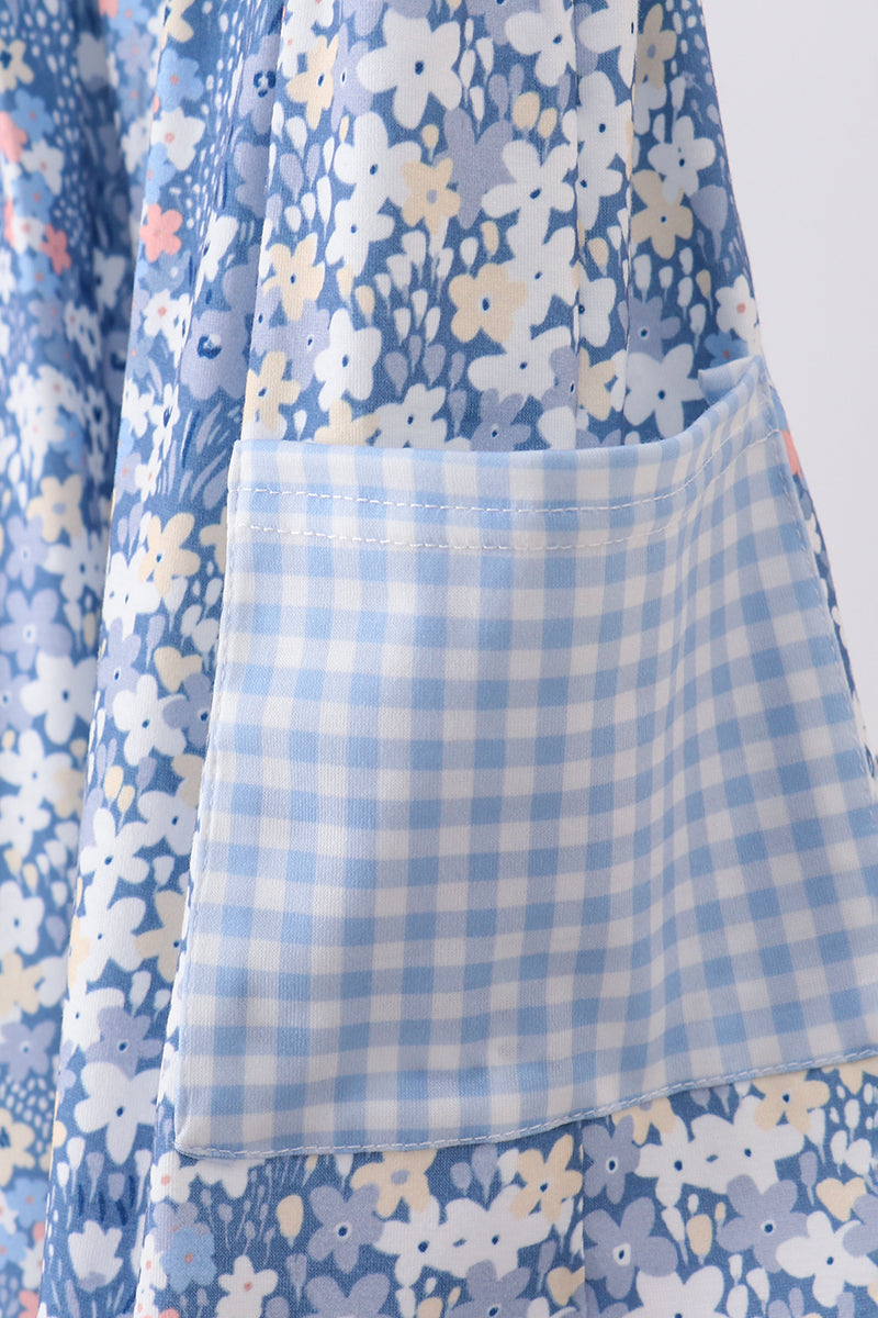 Close-up of a light blue and white gingham pocket on a dress with a blue, white, and yellow floral print.