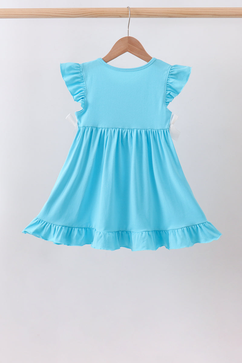 A light blue toddler girl's dress with ruffled cap sleeves and a ruffled hem, hanging on a wooden hanger against a plain light gray background.