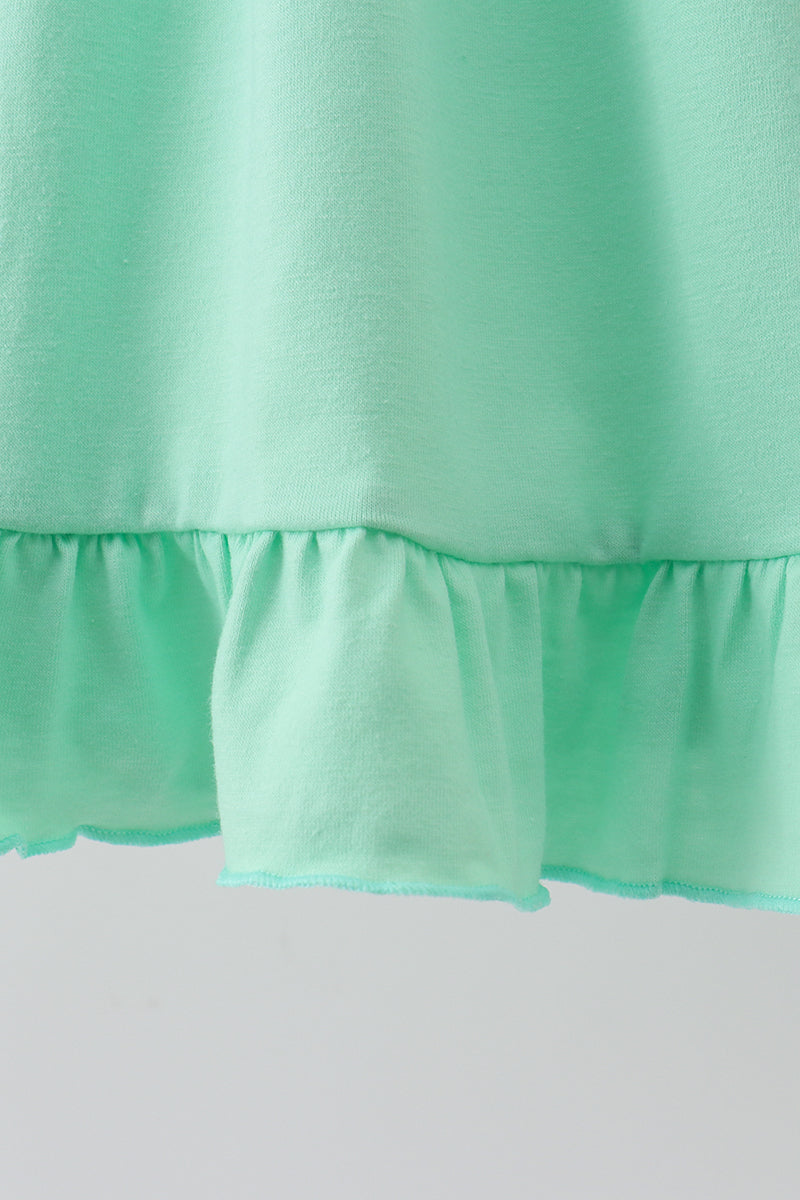Close-up of a mint green ruffled fabric, showing the texture and layered hem detail.