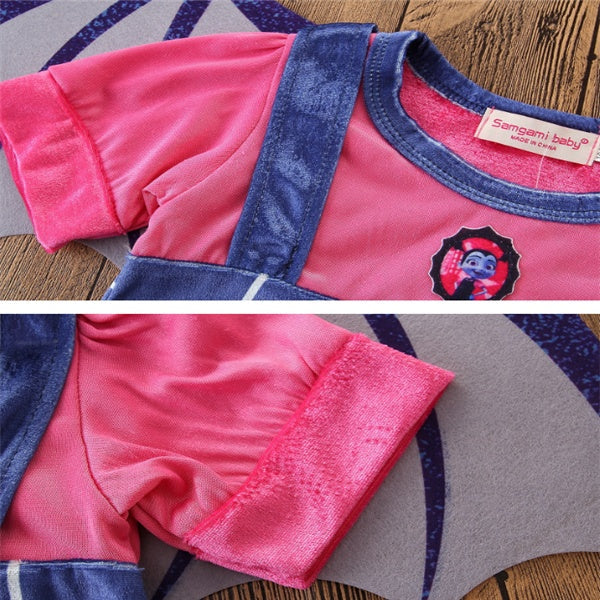Pink and blue children's outfit with a brand label on a wooden surface.