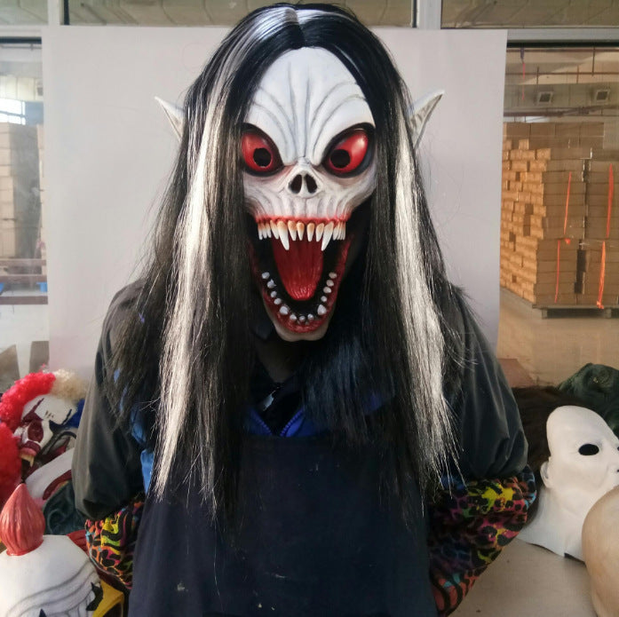 Person wearing a detailed mask with black hair and colorful clothing in an indoor setting.
