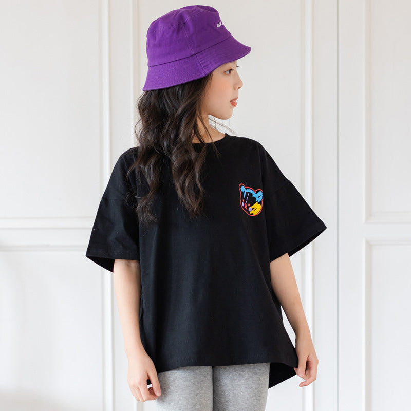 Person wearing a black t-shirt with a colorful logo and a purple bucket hat against a white background