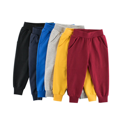 Five pairs of colorful sweatpants arranged in a row on a white background.