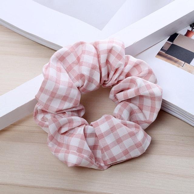 Pink and white checkered scrunchie on a light wooden surface