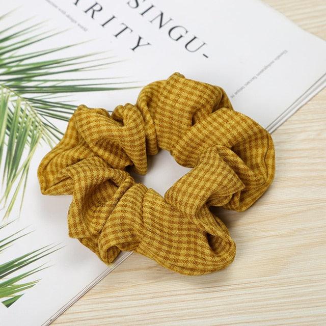 Mustard yellow scrunchie on a magazine with green leaves
