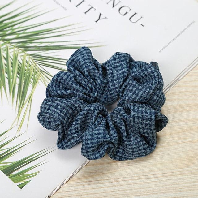 Blue checkered scrunchie on a magazine with green leaves
