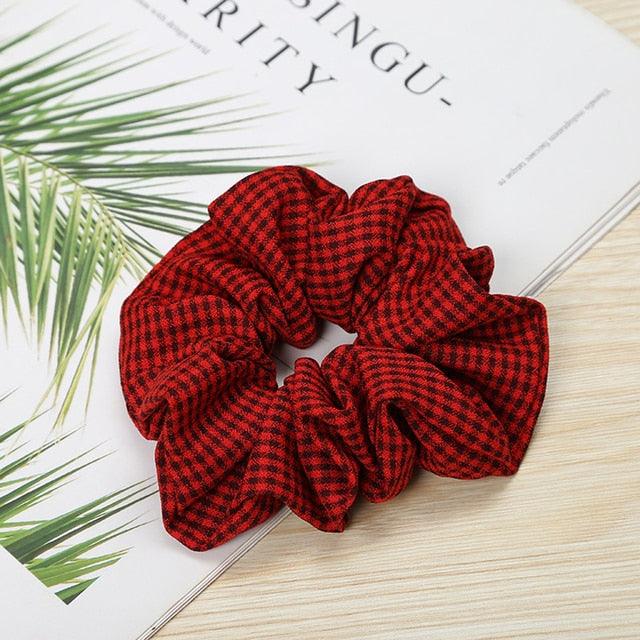 Red checkered scrunchie on a magazine with green leaves