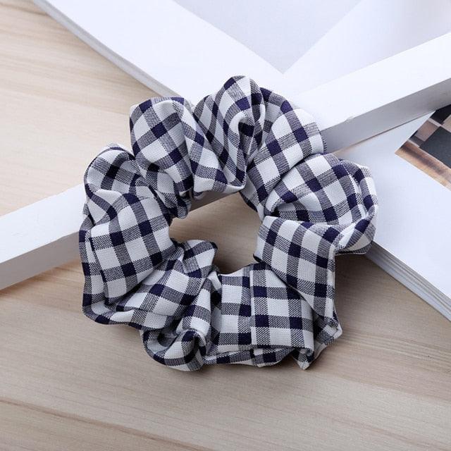 Black and white checkered scrunchie on a wooden surface with a white background