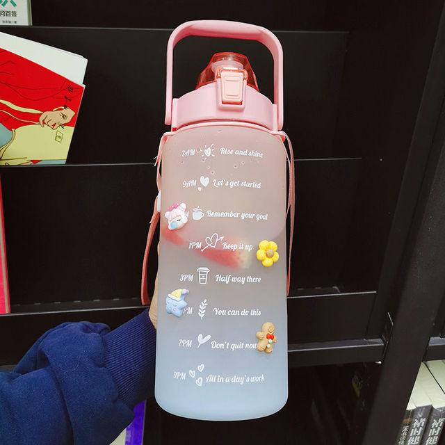 Pink water bottle with motivational text and graphics held by a person.