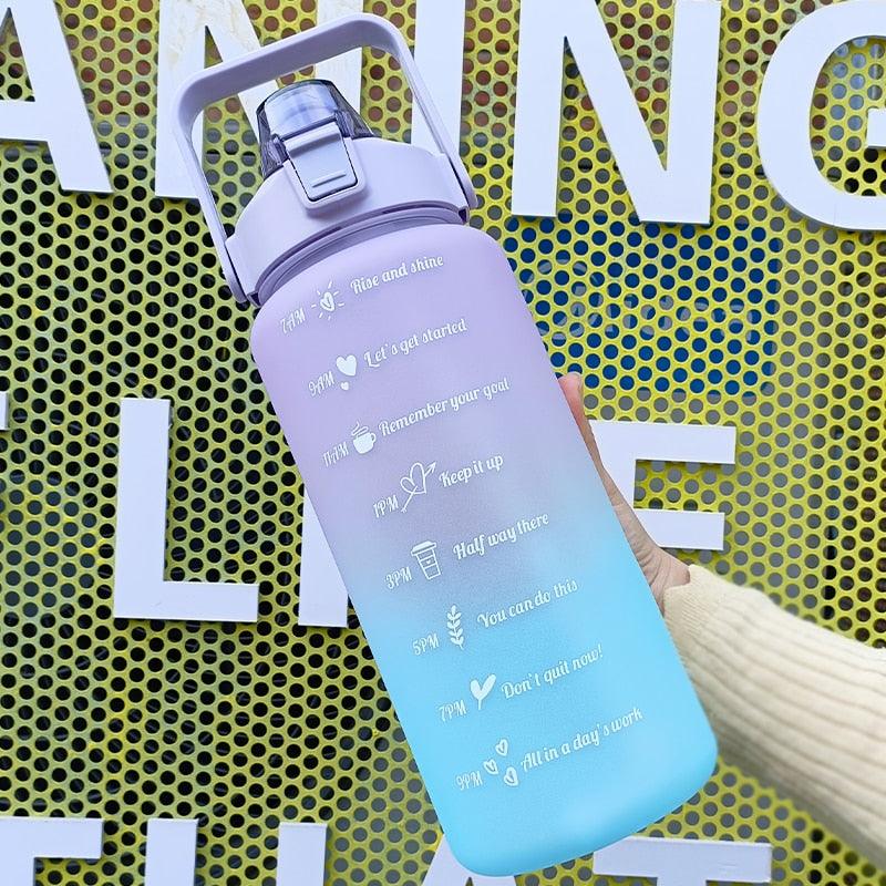 Gradient water bottle with text design held by a hand against a yellow textured background.