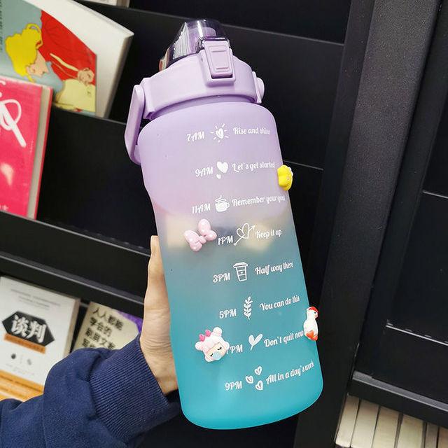 Purple and blue motivational water bottle with text and cartoon characters, held by a person.