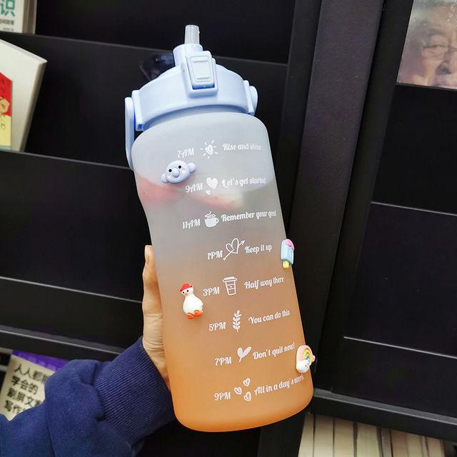Gradient water bottle with motivational phrases held by a person in a dark setting